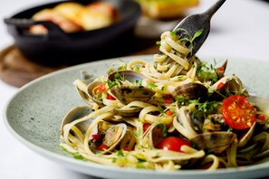 Un plato de pasta con almejas y tomates cherry.