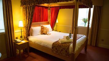 Una cama con dosel, una mesita de noche con lámpara y una ventana con cortinas.