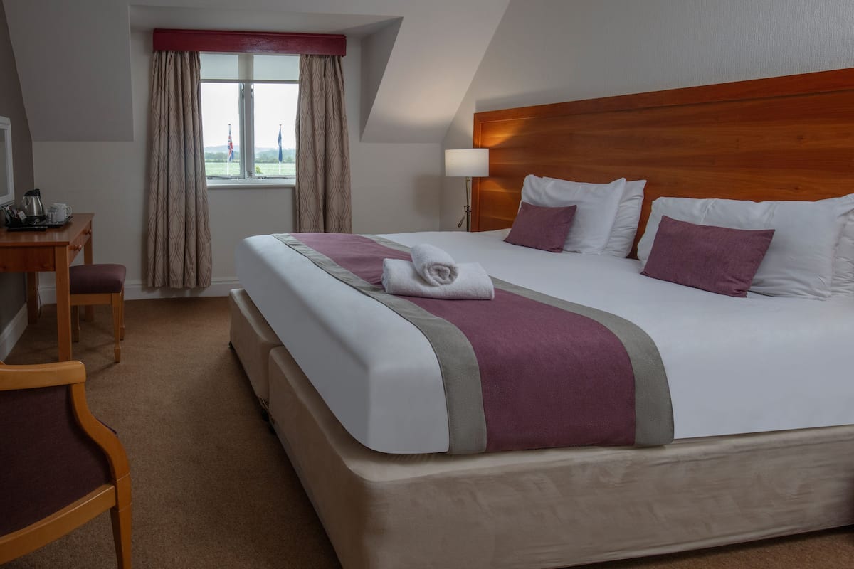 Habitación de hotel con una cama grande, un escritorio y una ventana con cortinas.