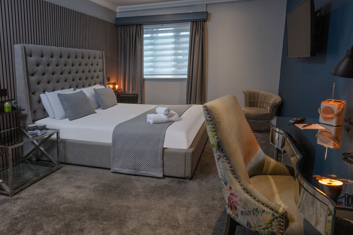 Una habitación de hotel moderna con una cama grande, un escritorio, una silla y un televisor.