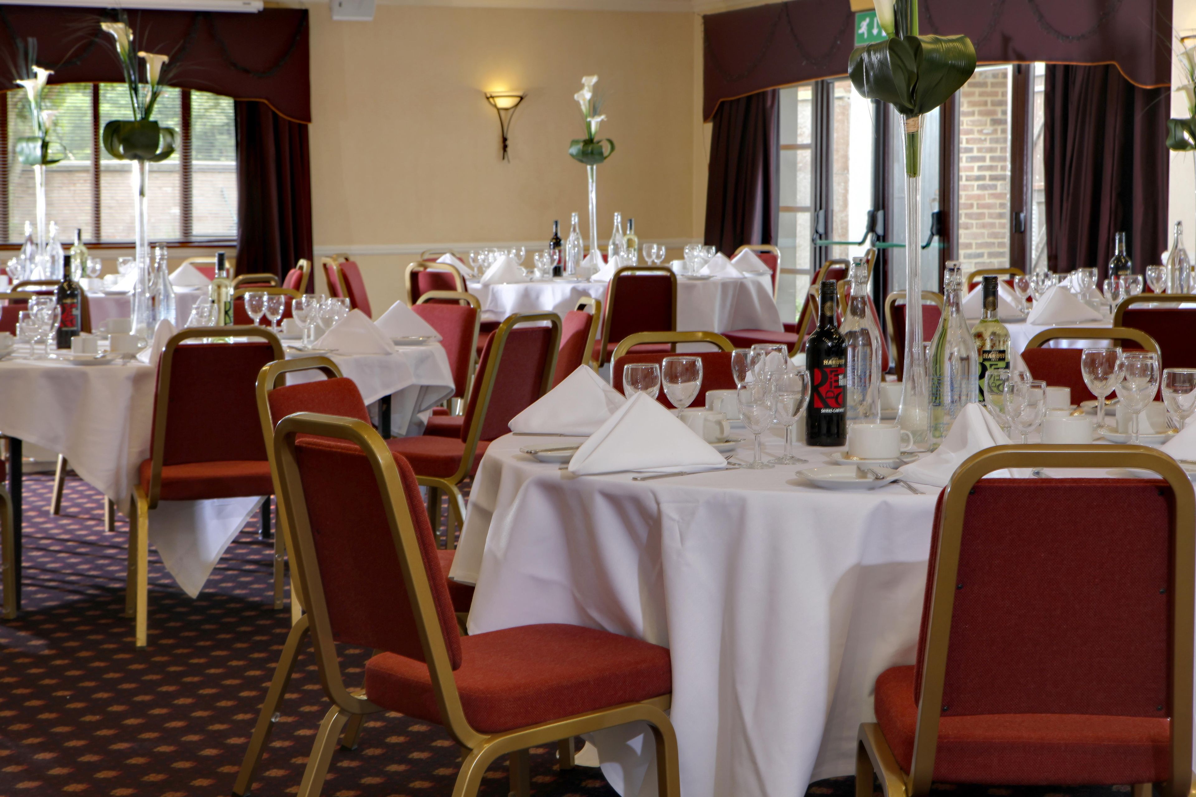 A dining area with tables set for service, chairs, and a chandelier.