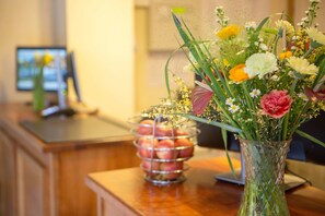 Ein Empfangstresen mit Blumenvase und Obstkorb.