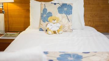 Cozy retreat with a plush bed, a teddy bear, and a nightstand with a lamp and reading material.