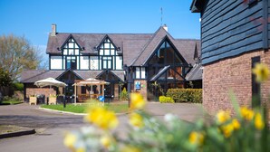 A large building with a prominent entrance, a covered outdoor seating area, and a well-maintained garden.