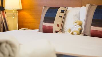 Ein Hotelzimmer mit einem Bett, einer Lampe und einem Teddy auf dem Kopfkissen.