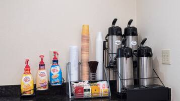 Un espace dédié au café, équipé de différents types de machines à café, de gobelets jetables et de condiments.