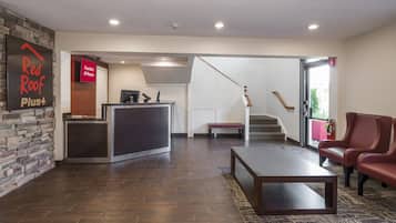 A reception area with a desk, a bench, a staircase, and a fire extinguisher.