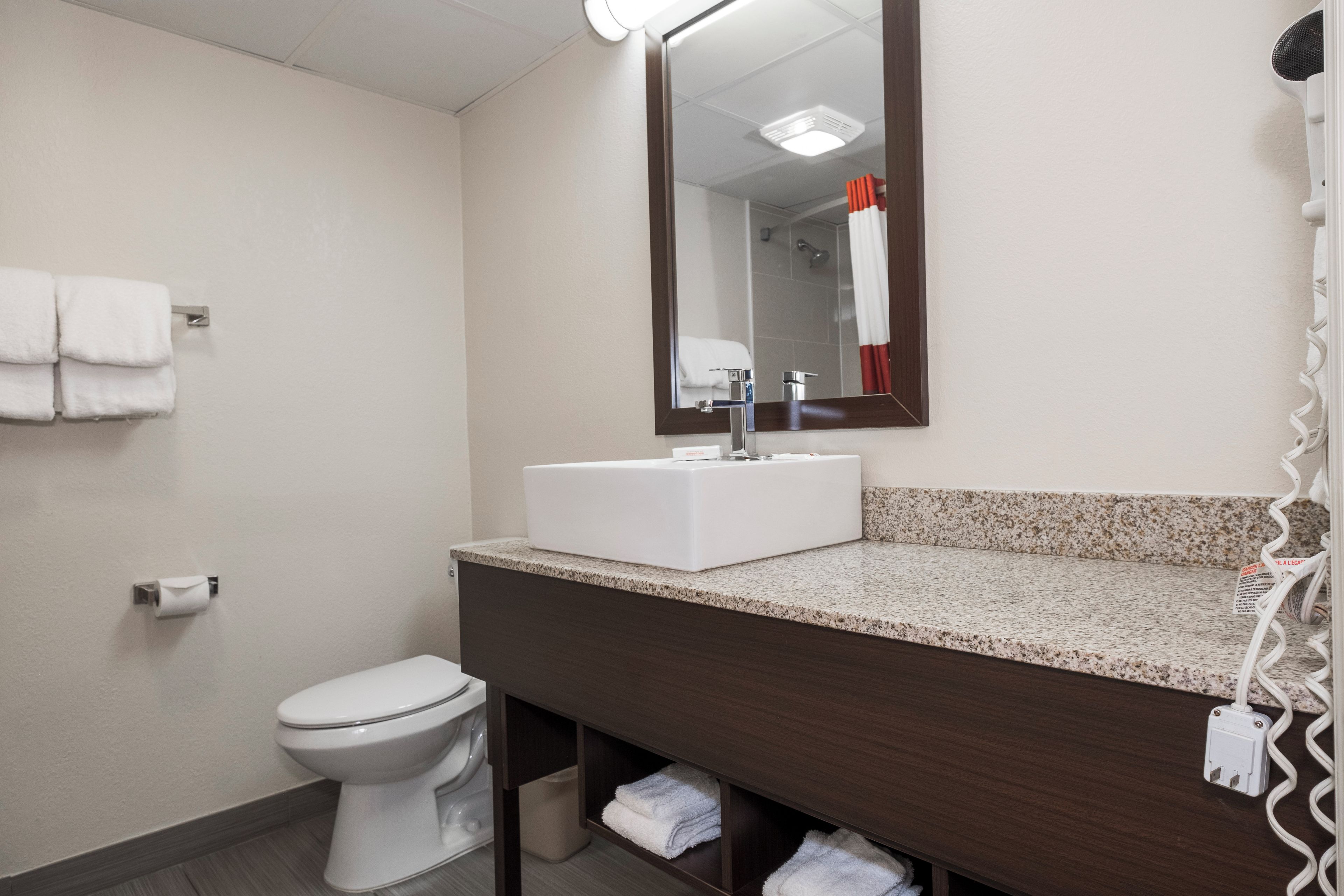 Un baño con inodoro blanco, lavabo con espejo y un perchero en la pared.
