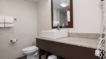 Un baño con inodoro blanco, lavabo con espejo y un perchero en la pared.
