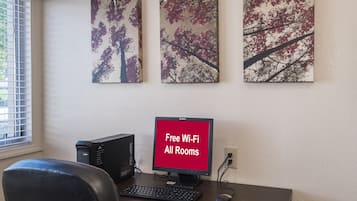 A workspace with a desktop computer, a keyboard, a mouse, and a monitor displaying 'Free Wi-Fi All Rooms'.