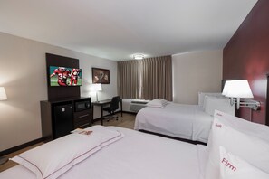 A hotel room with two beds, a desk, a television, and a window with curtains. - Red Roof Inn PLUS+ Poughkeepsie (Poughkeepsie)