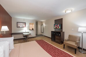 A hotel room with a bed, desk, chair, TV, and a small kitchenette. - Red Roof Inn PLUS+ Poughkeepsie (Poughkeepsie)