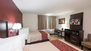 A hotel room with two beds, a desk, a television, a desk lamp, and a chair.