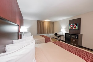 Habitación de hotel con dos camas, un escritorio, un televisor y un microondas.