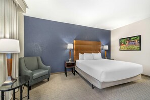 A hotel room with a large bed, a chair, a nightstand, a lamp, and a picture on the wall. - Drury Plaza Hotel Flagstaff (Flagstaff)