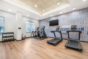 Un gimnasio con cintas de correr, mancuernas y equipo de ejercicio.