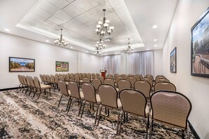 A conference room with rows of chairs, a podium, and ceiling lights. - Drury Plaza Hotel Flagstaff (Flagstaff)