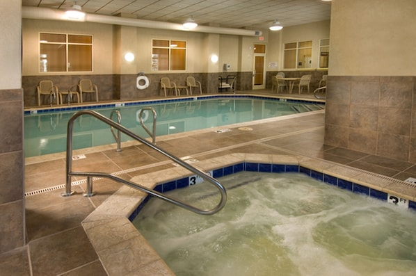 A hotel pool area with a hot tub, lounge chairs, and a tiled floor. - Drury Plaza Hotel Flagstaff (Flagstaff)