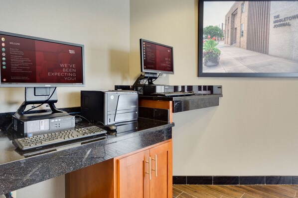 A reception area with two monitors displaying welcome messages, a desktop computer, a keyboard, and a printer. - Drury Inn & Suites Middletown Franklin (Franklin)