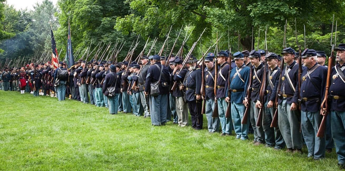 A line of uniformed individuals standing in formation on a grassy field.