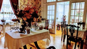 A dining area with a table set for a meal, surrounded by chairs and a vase of flowers. - Allegiance Bed and Breakfast (Mount Morris)