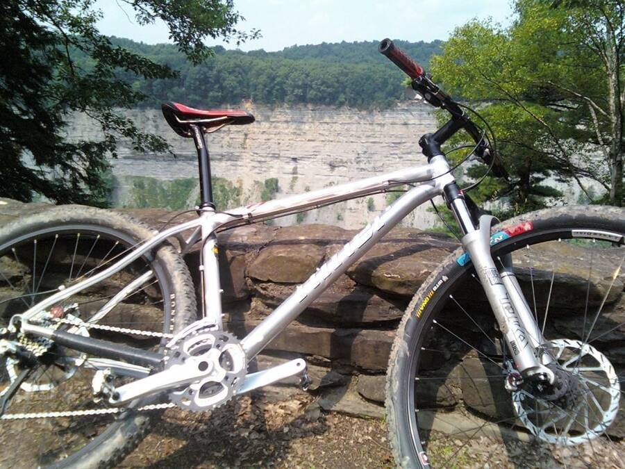 A mountain bike parked on a rocky ledge with a view of a canyon and forest in the background.