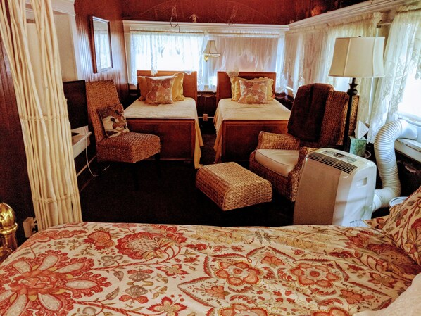 A room with two beds, a chair, a table, and a heater. - Allegiance Bed and Breakfast (Mount Morris)