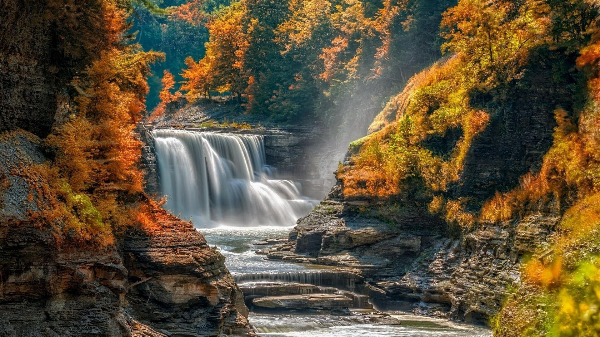A waterfall surrounded by rocky terrain and autumn foliage.