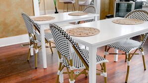 A dining area with a long white table, black and white checkered chairs, and woven placemats. - Beach Drive Inn (St. Petersburg)