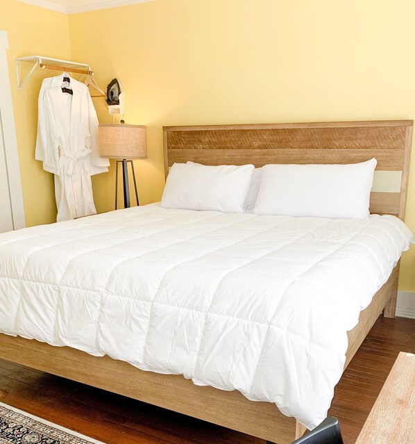 A neatly made bed with white bedding, a wooden headboard, and a bedside lamp.