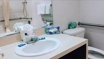 A bathroom with a white sink, a mirror, a toilet, and a towel rack.