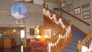 A lobby with a wooden staircase, a reception desk, and a seating area with a sofa and chairs.