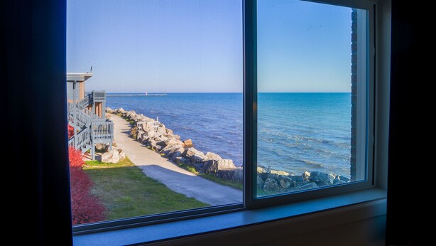 A view from a window overlooking a coastal area with a pathway leading to a building with a balcony.
