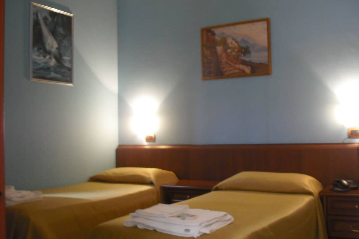 Ein Hotelzimmer mit zwei Betten, einem Nachttisch und zwei Wandlampen.