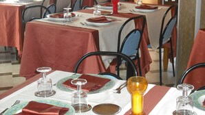 Un comedor con mesas dispuestas para varias personas, cada una con platos, cubiertos y vasos.