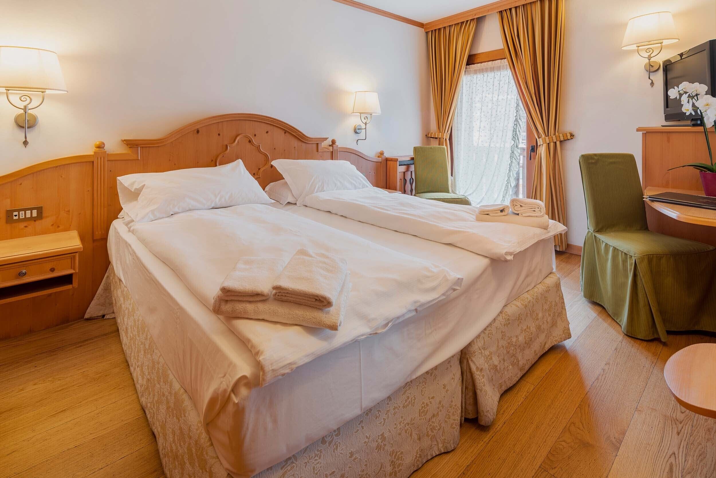 Ett hotellrum med en stor säng, två sängbord, en stol, ett skrivbord och en tv.