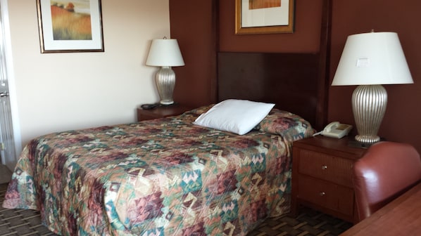 A hotel room with a bed, two bedside lamps, a telephone, and a framed picture on the wall.