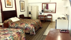 A hotel room with two beds, a desk, a refrigerator, a microwave, a chair, and a mirror.