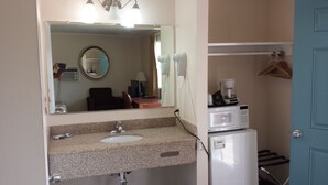 A bathroom with a sink, mirror, and a microwave.