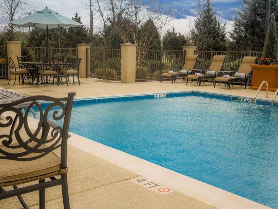 A pool area with a chair, a table, and a lounge chair.