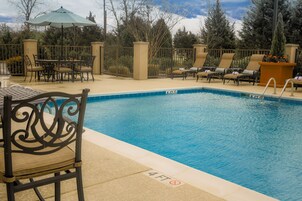 Zona de piscina con una silla, una mesa y un sillón de descanso.