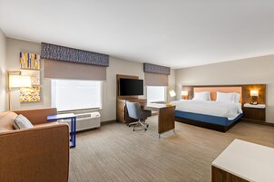A hotel room with a bed, desk, chair, and a television.