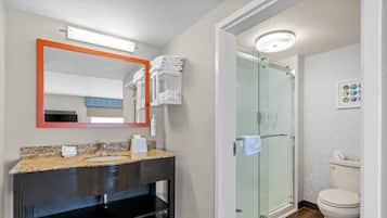 A modern bathroom with a granite countertop, a black vanity, a glass shower enclosure, and a toilet.