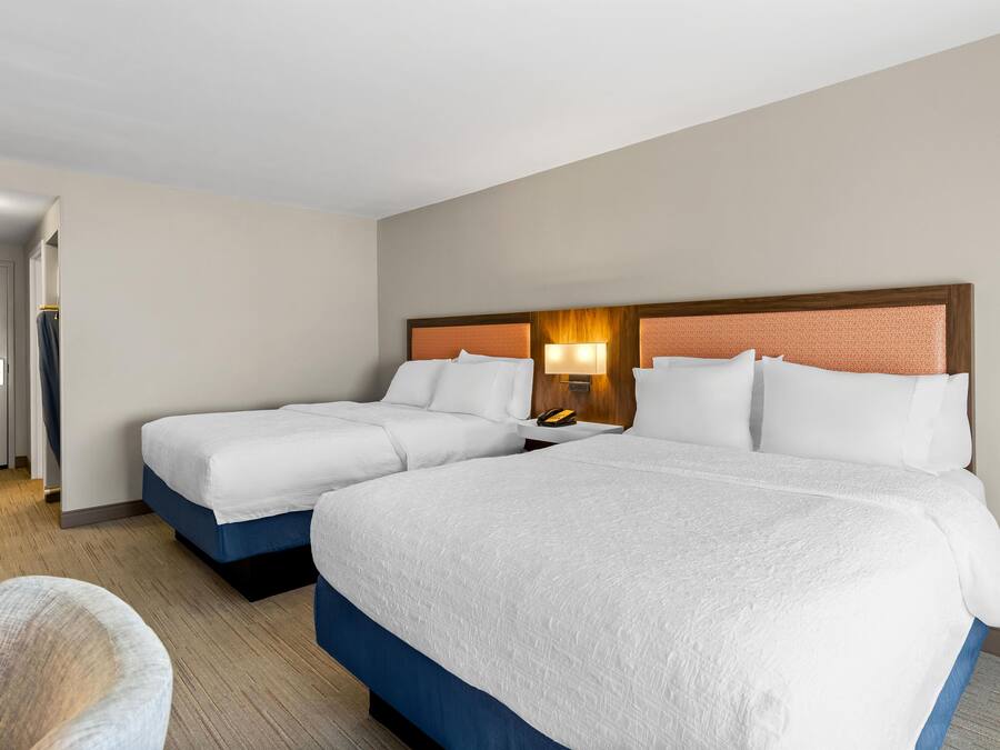 A hotel room with two beds, a desk, and a chair.