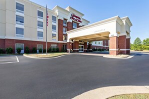 Un hôtel Hampton Inn & Suites doté d’une entrée couverte et d’un mât pour drapeau.