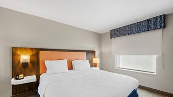 A hotel room with a large bed, two bedside lamps, a telephone, and a window with blinds.