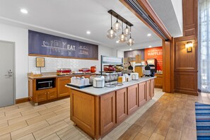 A modern kitchen with a breakfast bar, wooden cabinets, and a chalkboard menu. - Hampton Inn & Suites Murfreesboro (Murfreesboro)
