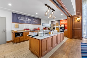 A modern kitchen with a breakfast bar, wooden cabinets, and a chalkboard menu.