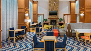 A hotel lobby with a stone fireplace, wooden paneling, and a variety of seating options including sofas and chairs.