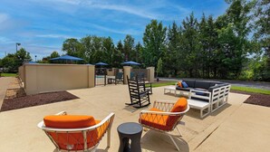 An outdoor patio area with seating arrangements, including chairs and a sofa, under blue umbrellas.